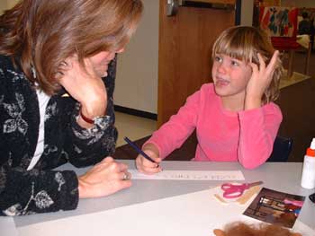 Amy was getting help from Mrs. George on how to write the title of her group's poster. 