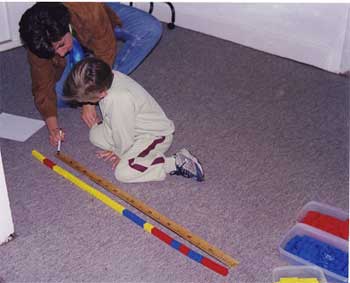 The teacher used a meter stick to measure the Unifix cubes a child used to represent the length of the machine.