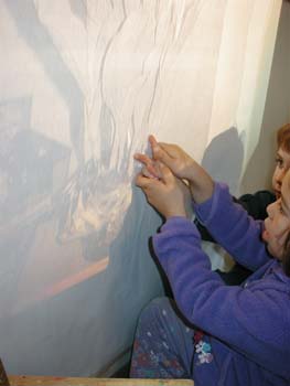 Figures 9-11. A child assists her peer in tracing shadows in preparation to paint.